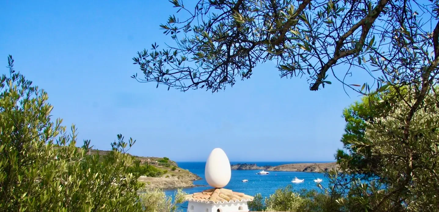 The bay of port lligat seen from Dali's house with a rooftop crowned by a large egg in the foreground