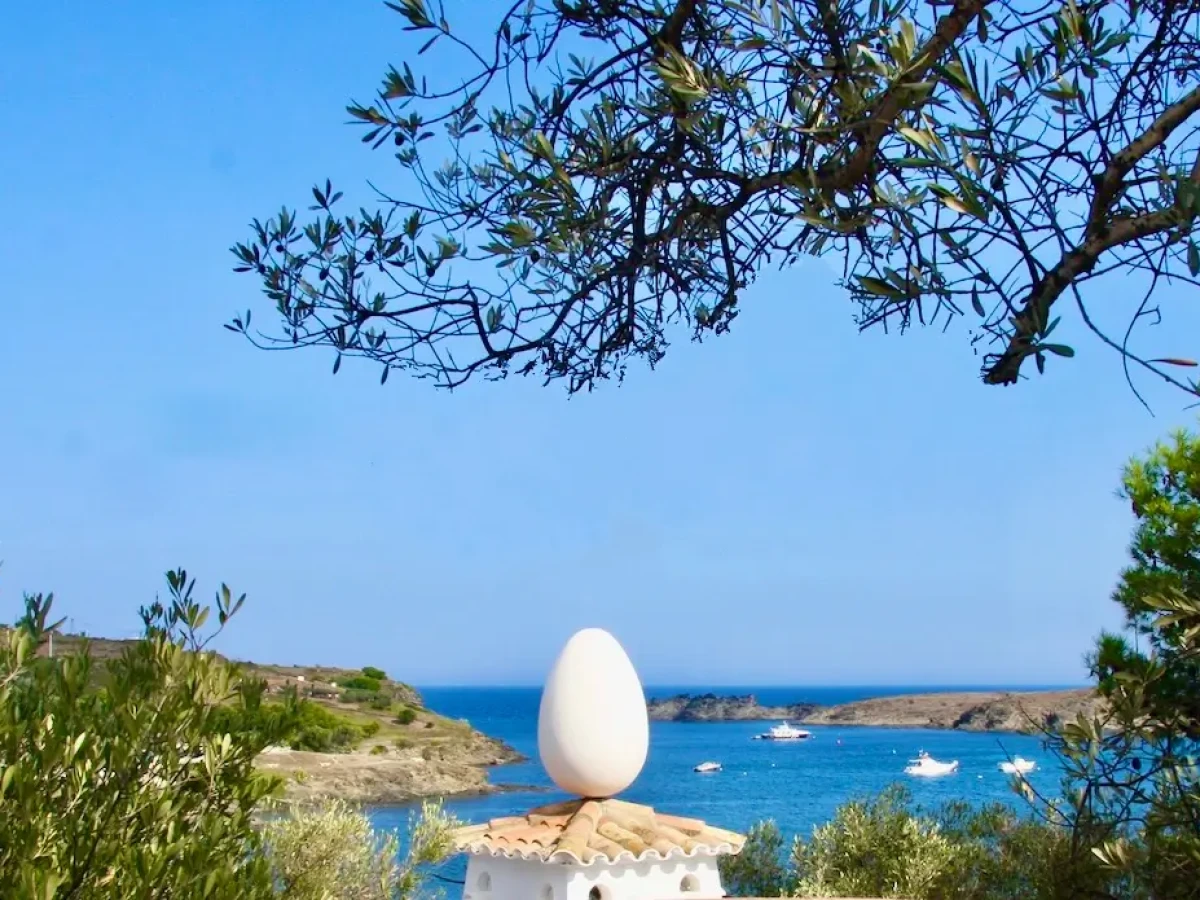 The bay of port lligat seen from Dali's house with a rooftop crowned by a large egg in the foreground